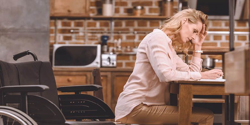 Woman at Desk Completing Paperwork with Empty Wheelchair Behind Her