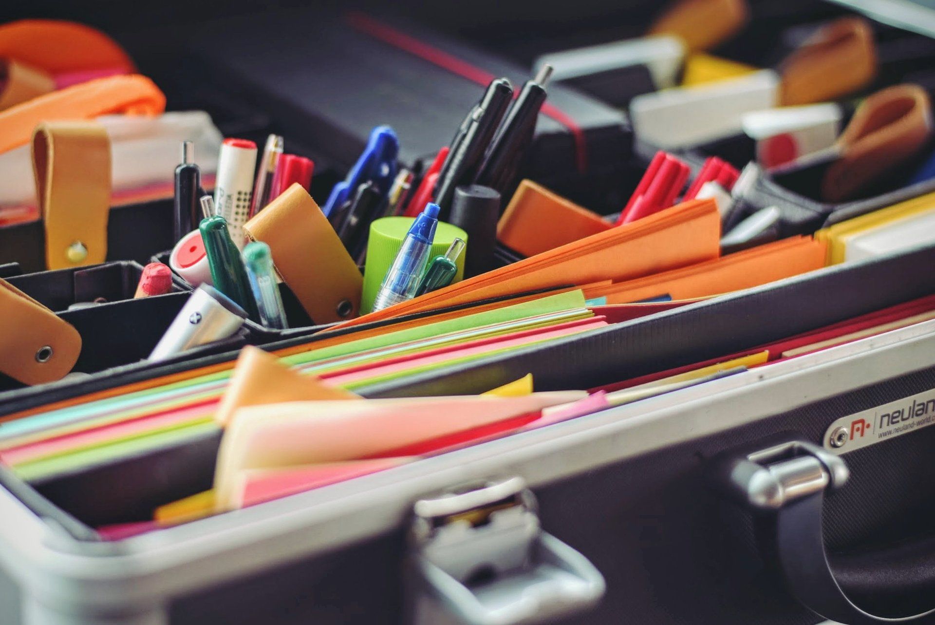 Open toolbox filled with pens, markers, erasers, and sticky notes.
