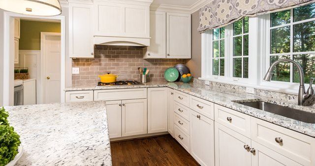 A kitchen with white cabinets , granite counter tops , and a sink.
