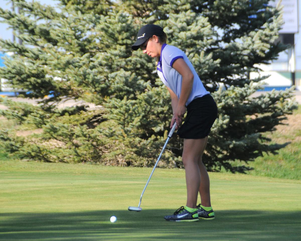 A woman is putting a golf ball on a green