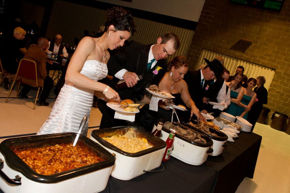 A bride and groom are getting food from a buffet line