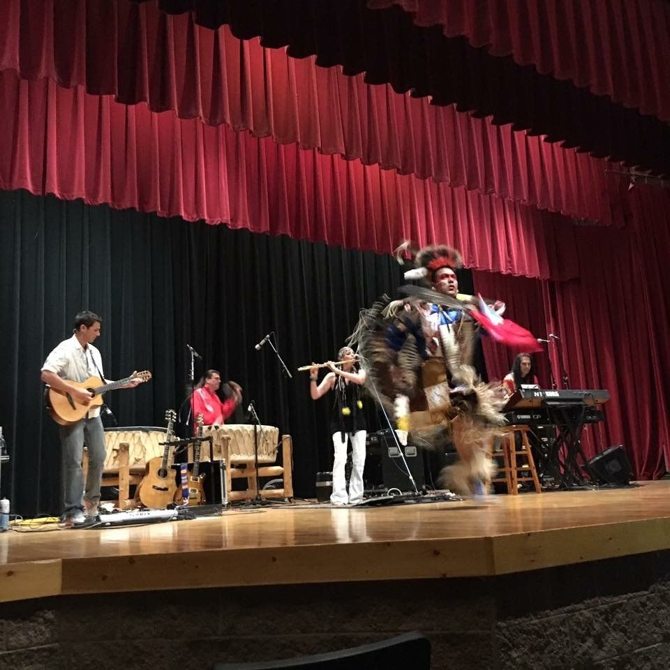 A group of people are performing on a stage with red curtains