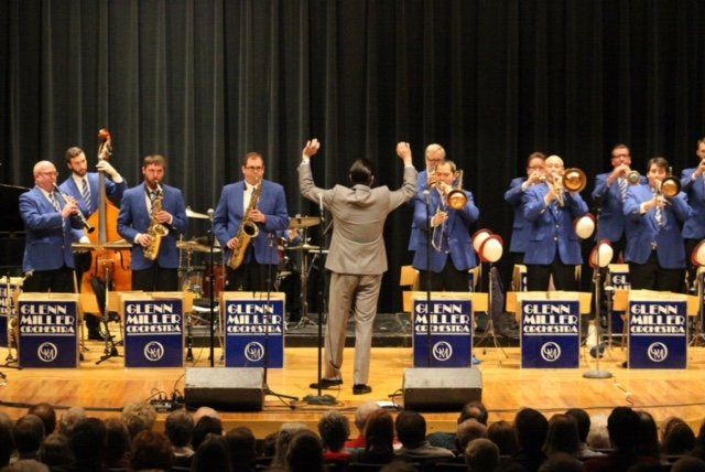 A man is leading a jazz band on a stage