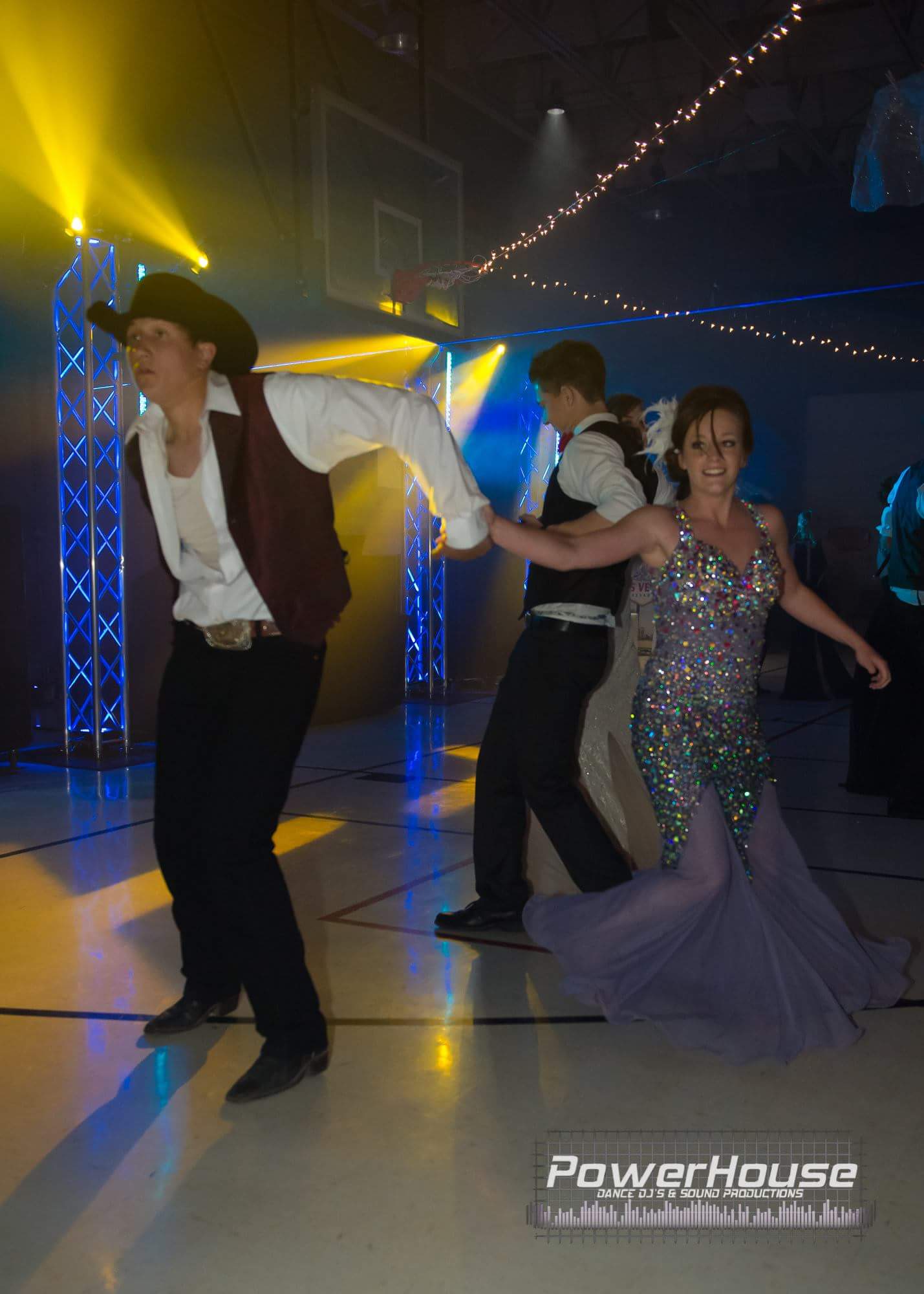 A man in a cowboy hat is dancing with a woman in a dress.
