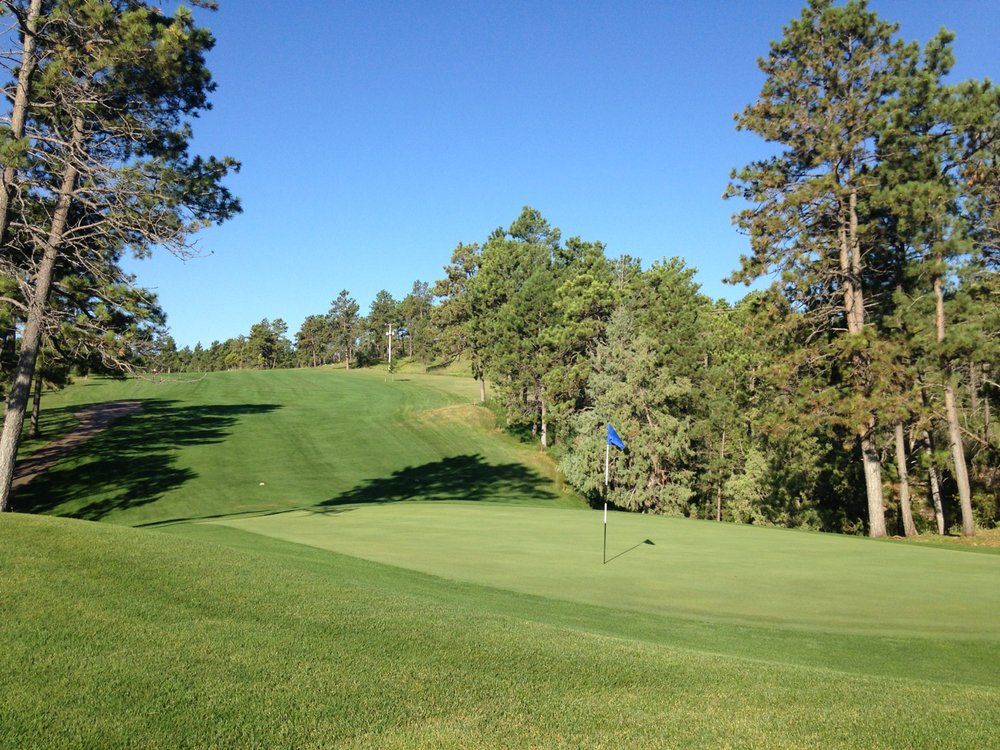 A golf course with a blue flag on the green