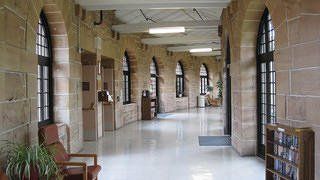 A long hallway with a lot of windows and chairs in a building.