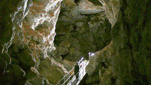A person is standing on a staircase in a cave.