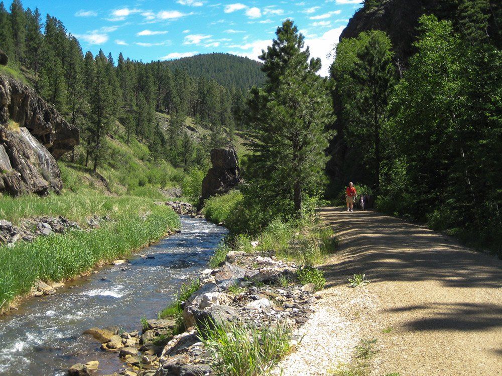 A person walking down a dirt road next to a river