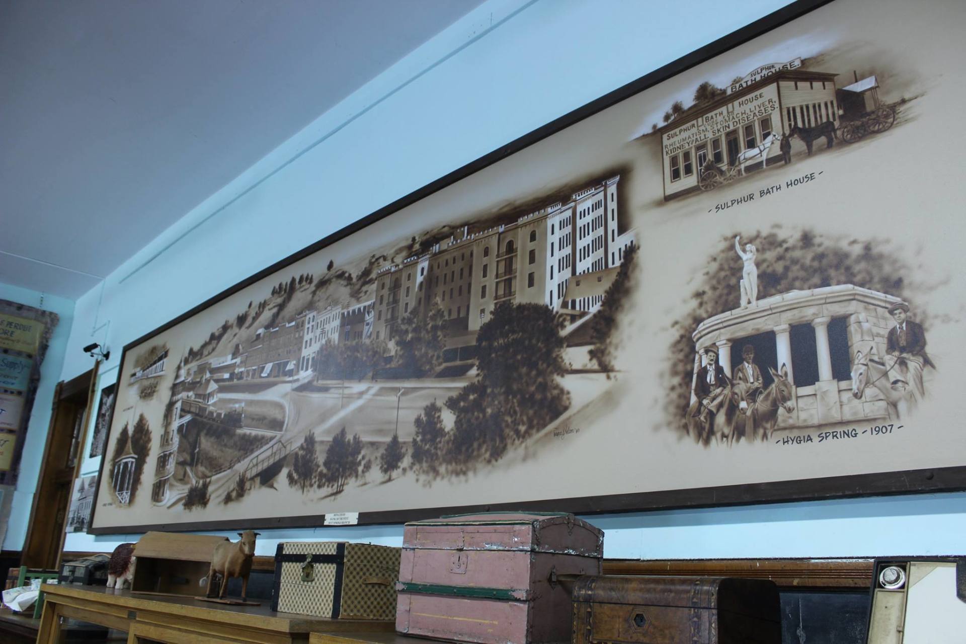 A large painting on a wall shows buildings and people