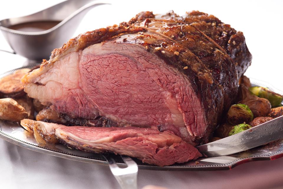 A large piece of meat is on a plate with vegetables and gravy.