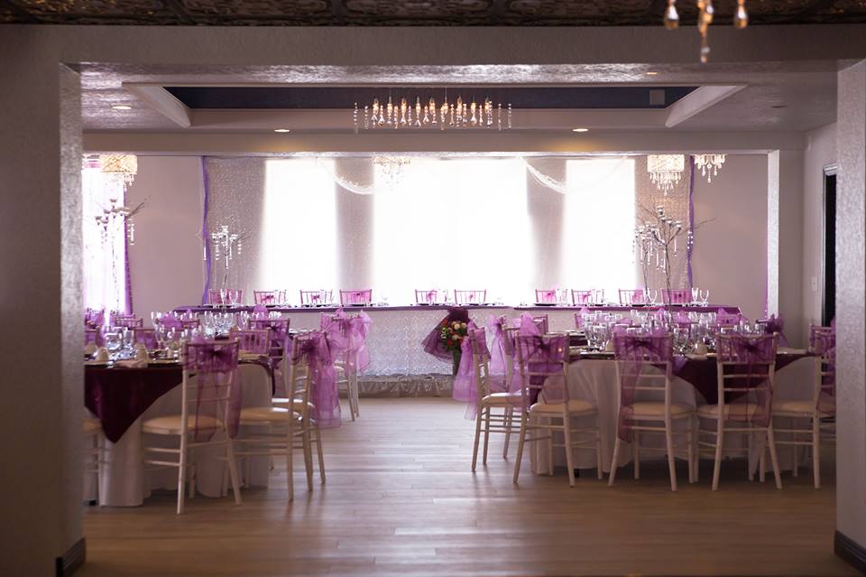 A large room with tables and chairs set up for a wedding reception.