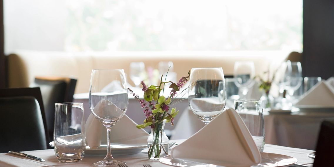 A restaurant table with a vase of flowers on it.