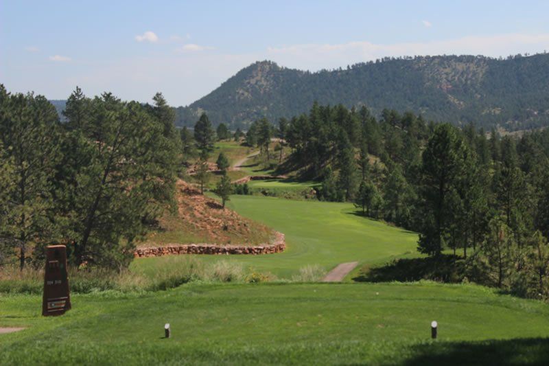 A view of a golf course with mountains in the background.