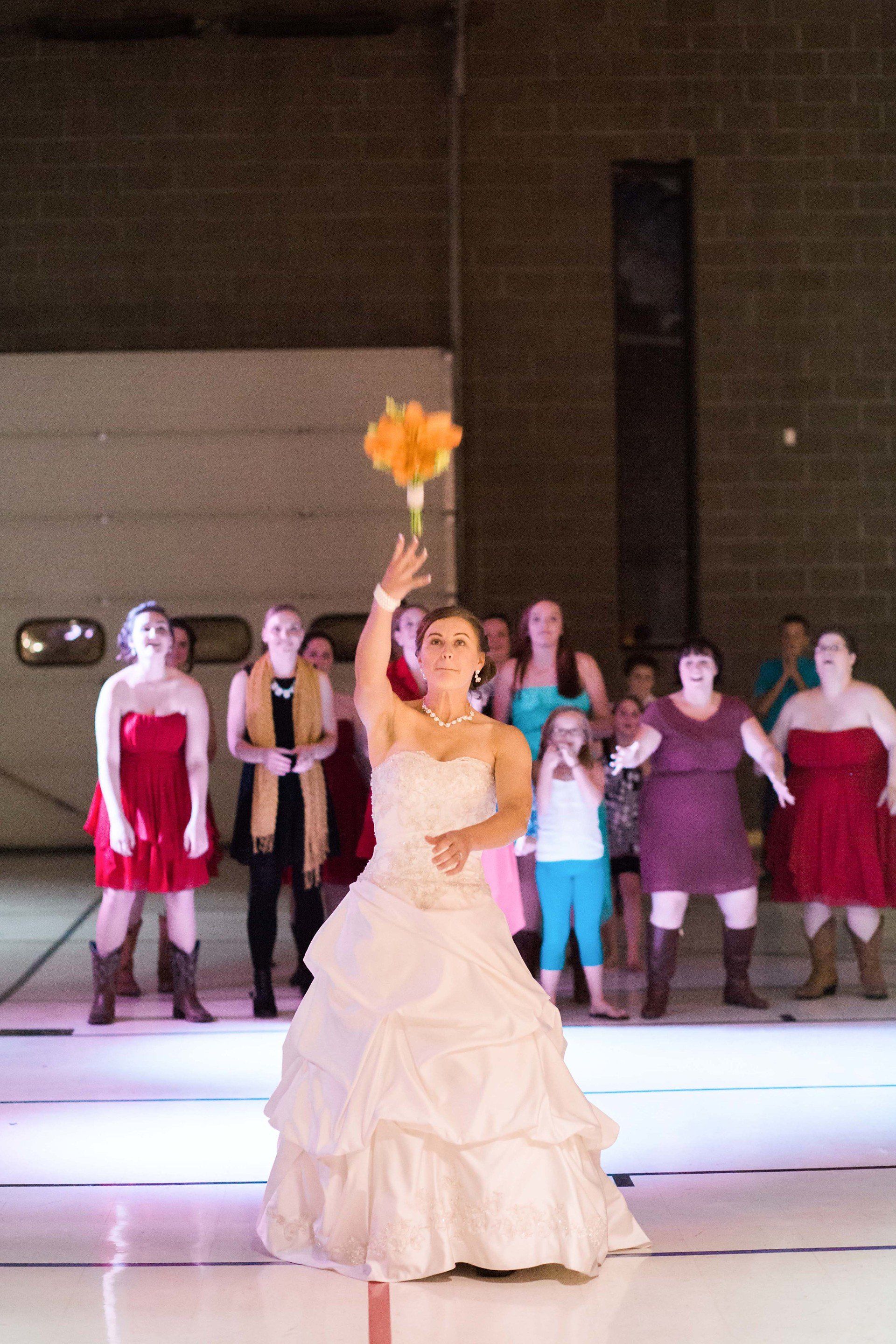 A woman in a wedding dress is throwing a bouquet of flowers