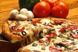 A pizza with pepperoni , olives , mushrooms and cheese is sitting on a wooden table.