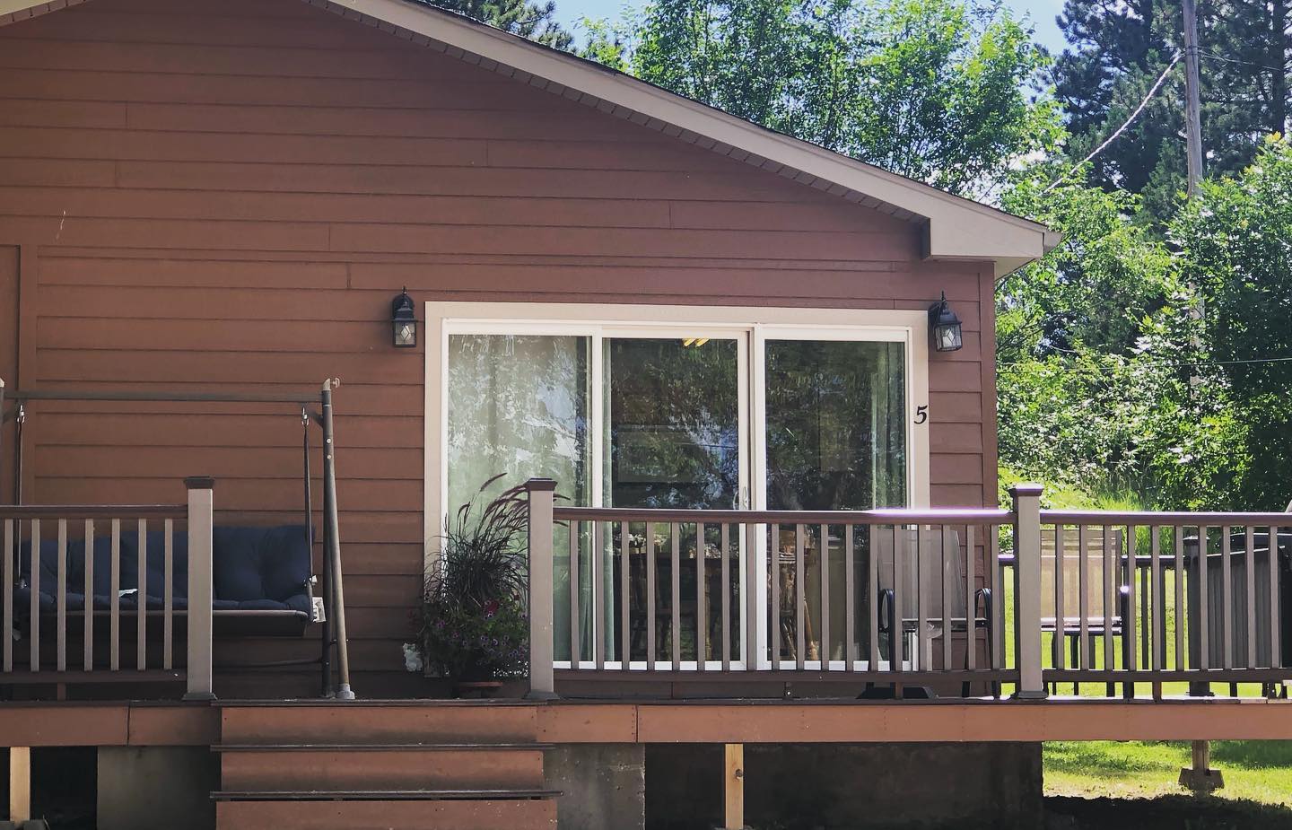 A small brown house with a sliding glass door and a deck.
