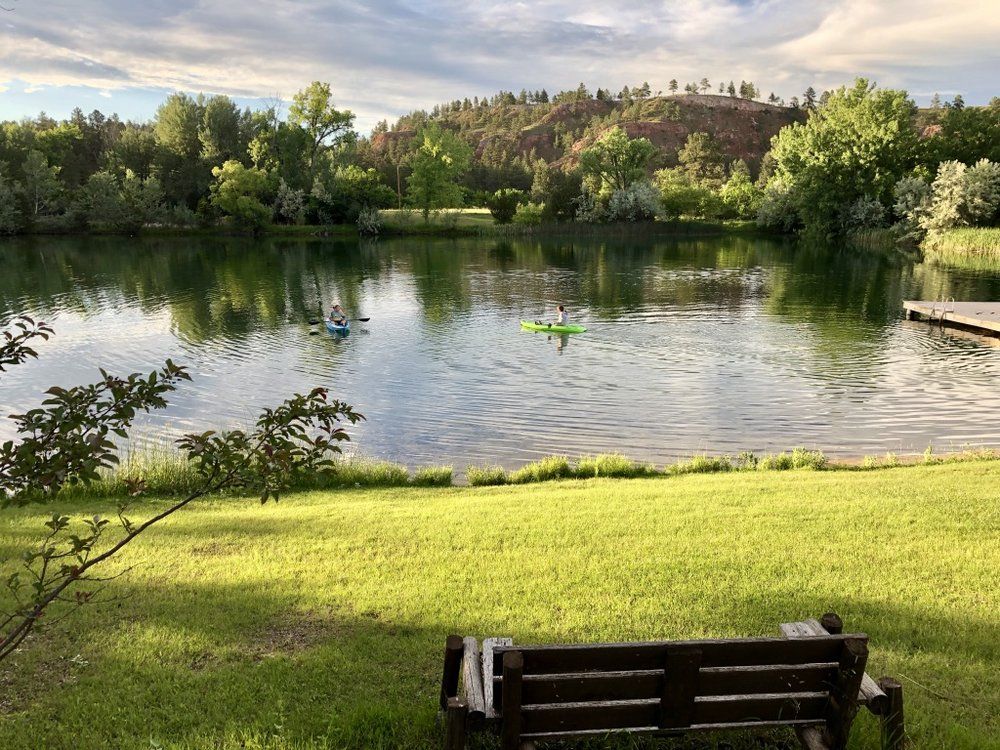 A wooden bench is sitting in the grass next to a lake.