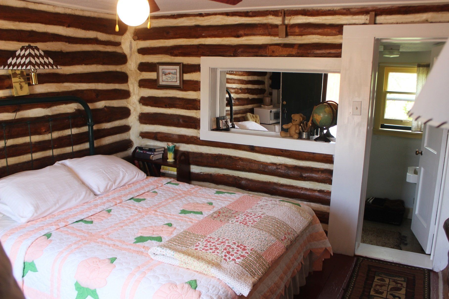 A bedroom in a log cabin with a bed and a mirror.