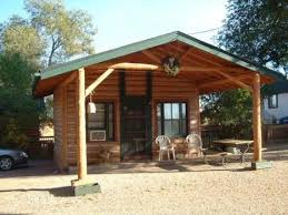 A small log cabin with a porch and chairs in front of it.