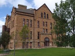 A large brick building with a lot of windows is sitting on top of a lush green field.