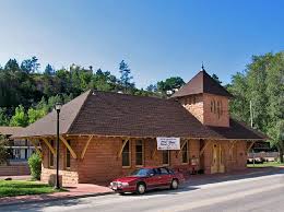 A red car is parked in front of a large brick building.