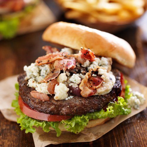 A hamburger with lettuce tomato and bacon on a bun