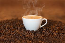A cup of coffee is sitting on top of a pile of coffee beans.