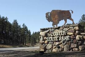 A statue of a bison standing on top of a stone wall.