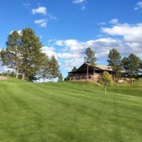 A house is sitting on top of a lush green hill next to a golf course.