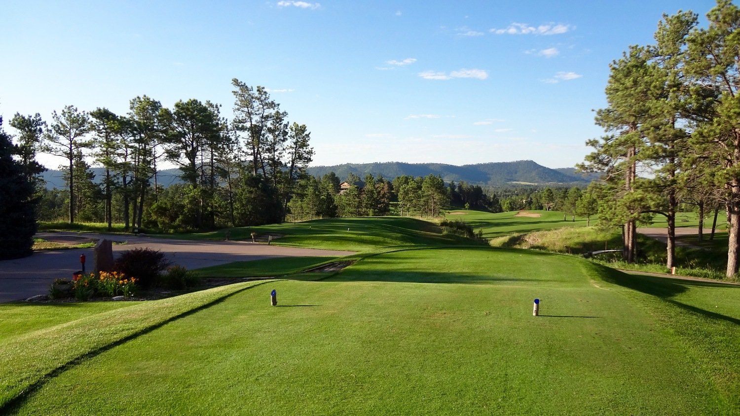 A golf course with trees and mountains in the background