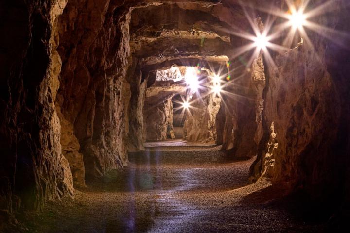 A dark cave with lights shining through the walls.