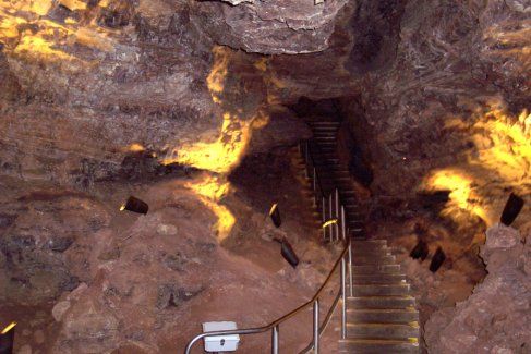 Stairs leading up to a cave with lights on the walls