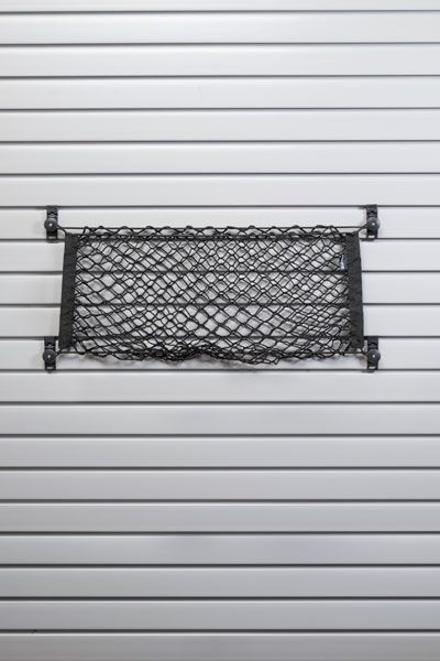 A black mesh bag is hanging on a slat wall.
