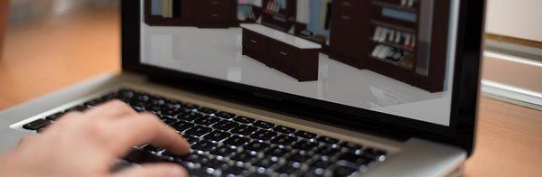 A person is typing on a laptop computer with a picture of a room on the screen.