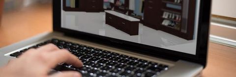 A person is typing on a laptop computer with a picture of a room on the screen.