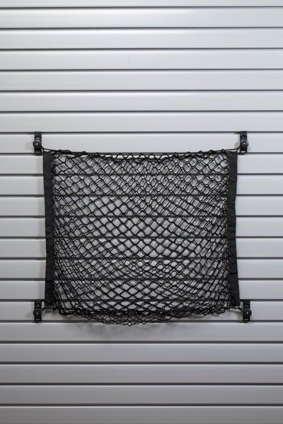 A black mesh bag is hanging on a wall.
