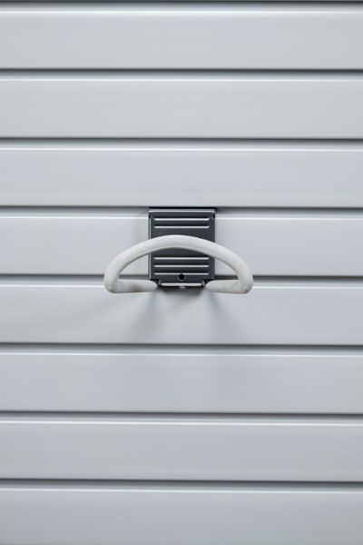 A white hook is hanging on a white wall.