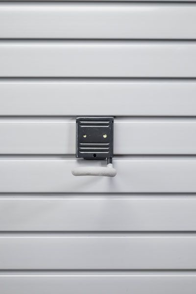 A close up of a white garage door with a hook on it.