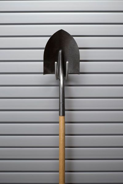 A shovel is hanging on a hook on a wall.