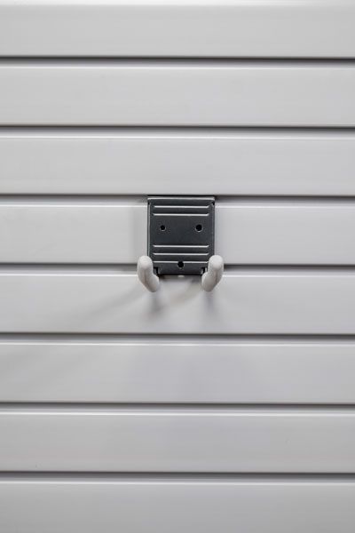 A hook is hanging on a white slat wall.