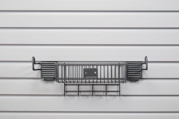 A gray basket is hanging on a white wall.