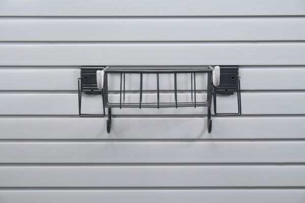 A black basket is hanging on a white wall.