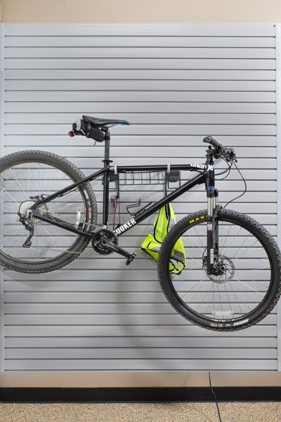 A bicycle is hanging on a wall in a garage.
