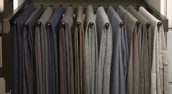 A closet filled with lots of pants hanging on a rack.