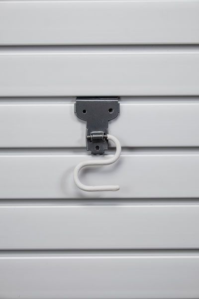 A white hook is hanging on a white wall.