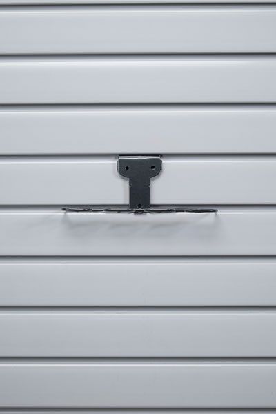 A close up of a white garage door with a black hook on it.