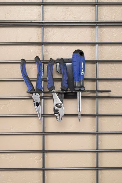 A pair of pliers and a screwdriver are hanging on a wire rack.