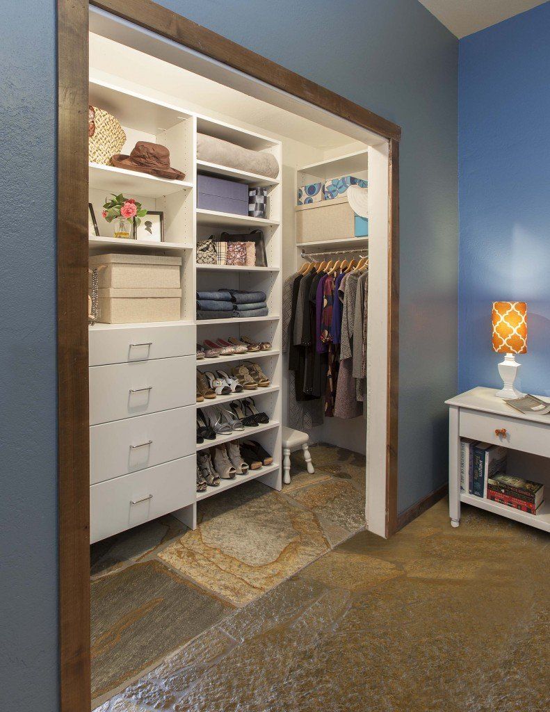 A walk in closet in a bedroom with blue walls and a nightstand.
