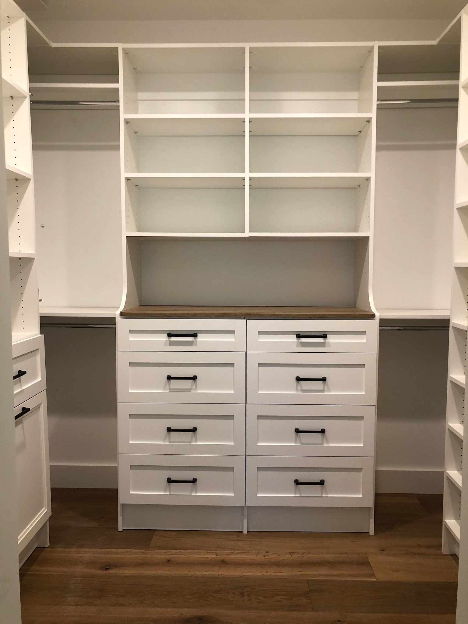 A walk in closet with lots of shelves and drawers.