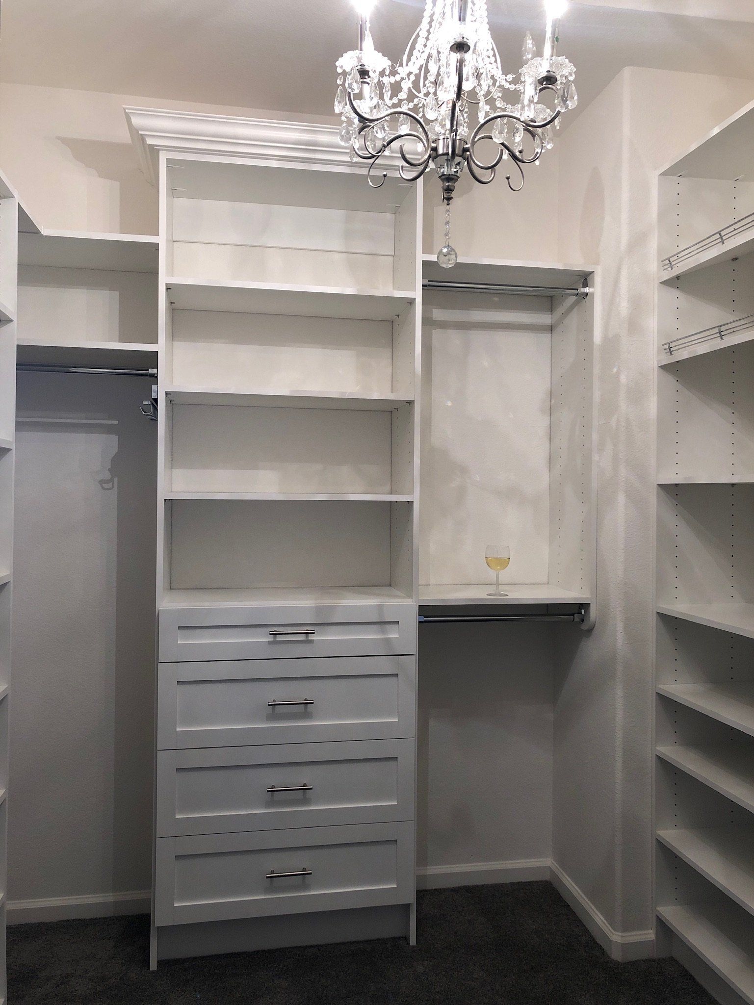 A walk in closet with a chandelier hanging from the ceiling.